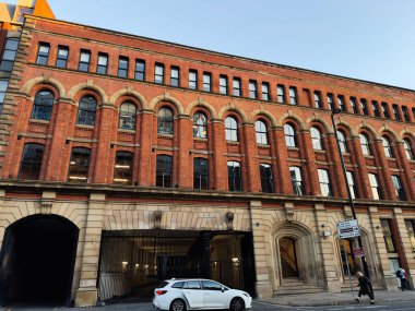 Manchester, İngiltere - 23 Eylül 2025: Büyük kemerli pencereleri ve Portland st. 'te taş girişi olan tarihi Manchester binasının kırmızı tuğla cephesi. 