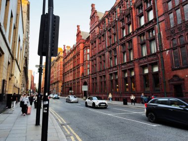 Manchester, İngiltere - 23 Eylül 2025: Kırmızı tuğlalı mimari, arabalar ve yayalarla dolu Manchester caddesi.