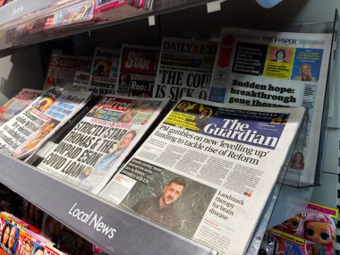 Londra, İngiltere - 26 Eylül 2025: Guardian ve diğer gazetelerin ön sayfalarıyla dolu yoğun bir gazete bayii, basılı gazetecilik ve günlük yayınlar sergileniyor.