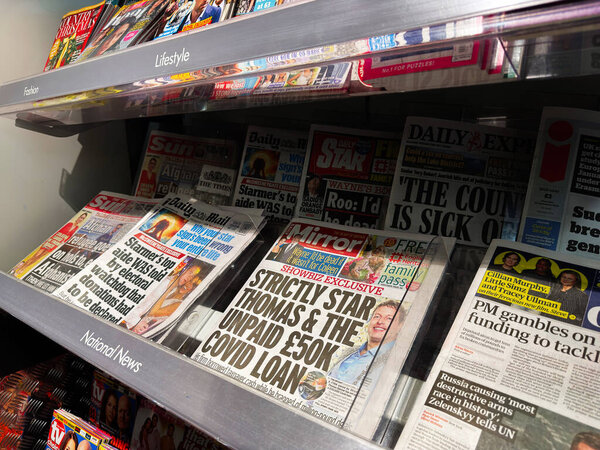 Лондон, Великобритания - 26 сентября 2025 года: На полке газетного киоска выставлены таблоиды и ежедневные газеты с яркими заголовками и красочными обложками.