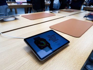 Manchester, İngiltere - 29 Eylül 2025: Tabletler ve Apple Watch serisi 11 yakınlardaki müşterilerle birlikte işlek bir perakende satışta..