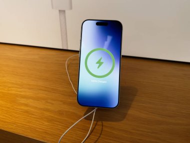 Manchester, İngiltere - 29 Eylül 2025: Bir telefon iPhone 17 Pro ahşap bir masada, tam pil göstergesi ile kablosuz şarj ediliyor.