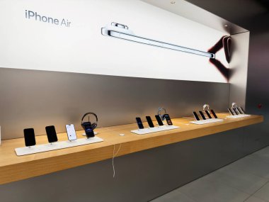Manchester, İngiltere - 29 Eylül 2025: Pürüzsüz bir perakende ortamında ahşap bir ekranda bir sıra iPhone Air akıllı telefon ve kulaklık.