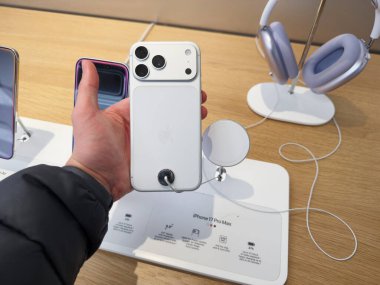 Manchester, İngiltere - 29 Eylül 2025: Bir tüketici, yakınlarda kablolu güvenlik kablosu ve kulaklığı bulunan bir mağaza vitrininde beyaz bir iPhone 17 Pro 'yu inceliyor.