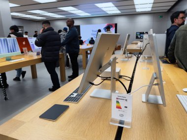 Manchester, İngiltere - 29 Eylül 2025: Müşteriler Apple cihazlarını parlak bir galeride, gösterişli masalarda, tabletlerde ve aksesuarlarda keşfediyorlar.