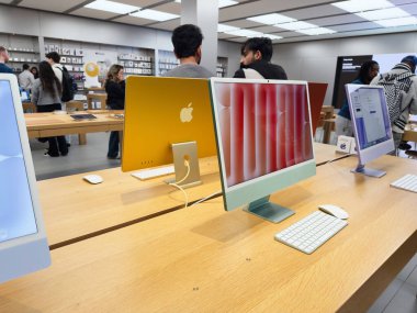 Manchester, İngiltere - 29 Eylül 2025: Pürüzsüz iMacler, klavyeler ve keşfeden müşteriler ile parlak elektronik galeri sahnesi.