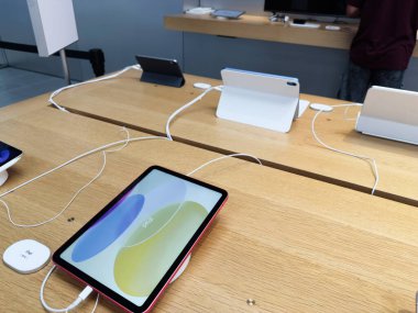 Manchester, İngiltere - 29 Eylül 2025: Ahşap masalarda beyaz şarj kabloları olan bir iPad 'in yer aldığı perakende teknoloji galerisi.