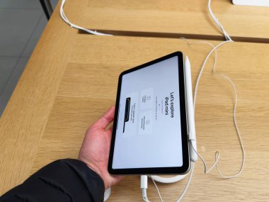 Manchester, İngiltere - 29 Eylül 2025: Bir el modern çalışma alanındaki ahşap bir masada Apple kalem ile bir iPad mini tutuyor.