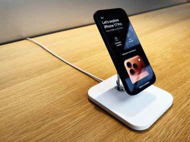 Manchester, İngiltere - 29 Eylül 2025: Pürüzsüz iPhone 17 Pro bir mağazada beyaz şarj standı üzerinde, bir perakende satış ortamında teknoloji ve tasarımı vurguluyor.