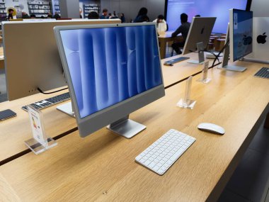 Manchester, İngiltere - 29 Eylül 2025: Meşgul bir elektronik mağazasında parlak ahşap bir masa üzerindeki iMac masaüstleri.