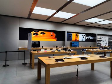 Manchester, İngiltere - 29 Eylül 2025: Ahşap masalarda iPhone cihazları, parlak ışıklandırma ve tanıtım afişleri olan şık bir elektronik mağazası.