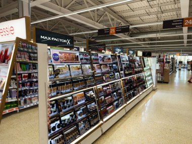 Salford, İngiltere - 25 Eylül 2025: Sainsbury 'nin süpermarketinde makyaj malzemeleri ve marka tabelasıyla parlak kozmetik reyonu.
