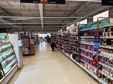 Salford, İngiltere - 25 Eylül 2025: Müşteriler İngiltere 'de kozmetik, saç bakımı ve tuvalet malzemeleriyle dolu bir süpermarket koridorunu keşfediyorlar..