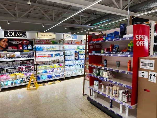 Salford, İngiltere - 25 Eylül 2025: İyi organize edilmiş raflarda kozmetik, cilt bakımı ve kişisel bakım ürünleri içeren Bright Sainsbury süpermarket koridoru.