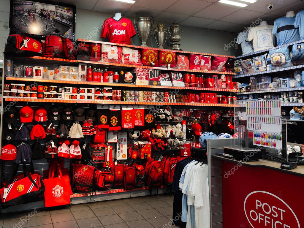Manchester, UK - September 25, 2025: Manchester United shop interior featuring red merchandise, hats, bags, jerseys, and trophies on display.