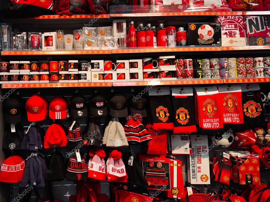 Manchester, UK - September 25, 2025: A crowded football team shop display of red and black hats scarves mugs and other merchandise.