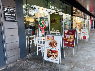 Manchester, İngiltere - 25 Eylül 2025: Yoğun bir şehir caddesinde tanıtım panoları ve oturma yerleri olan bir İtalyan restoranının açık hava görüntüsü.