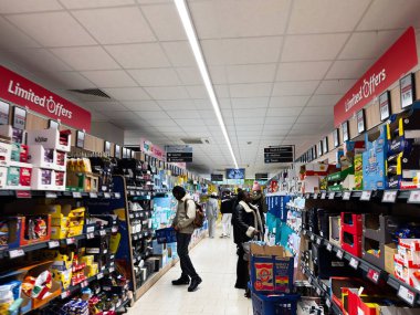 Manchester, İngiltere - 25 Eylül 2025: Parlak bir mağazada raflara ve satış tabelalarına bakan müşterilerle dolu Lidl süpermarket koridoru.