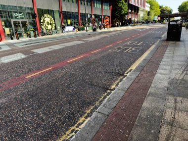 Manchester, İngiltere - 25 Eylül 2025: Yayalar, dükkanlar ve tuğla kaldırım boyunca görünen yol işaretleriyle dolu canlı bir Manchester şehri sokak sahnesi.