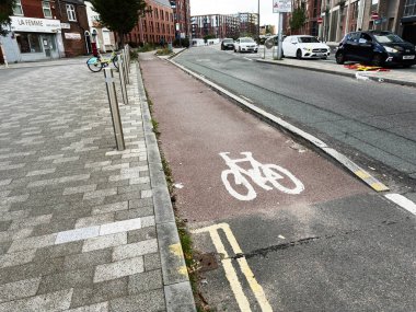 Manchester, İngiltere - 25 Eylül 2025: Manchester 'da işlek bir şehir caddesinde bisiklet yolunda dükkan önlerinin yanında boyalı bir bisiklet sembolü gösteriliyor.
