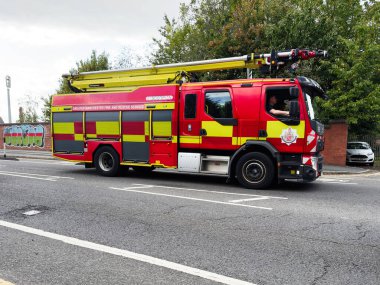 Manchester, İngiltere - 25 Eylül 2025: Merdivenli ve mürettebatlı kırmızı itfaiye aracı, acil müdahale için hazır.