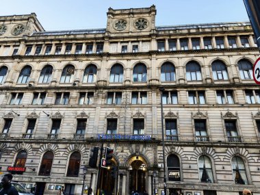 Manchester, İngiltere - 25 Eylül 2025: Büyük Manchester şehir binasının kemerli camları, parmaklıkları ve kentsel yaşam işaretleri olan tarihi taş cephesi.