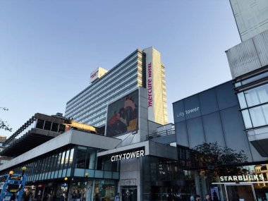 Manchester, İngiltere - 25 Eylül 2025: Şehir Kulesi, Mercure Hotel ve Starbucks vitrinlerinin altında açık gökyüzü bulunan şehir alışveriş merkezi.