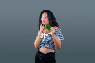 Güzel, genç, Çinli bir kadın elinde kartla ve zarif bir tereddüt ifadesi ile.