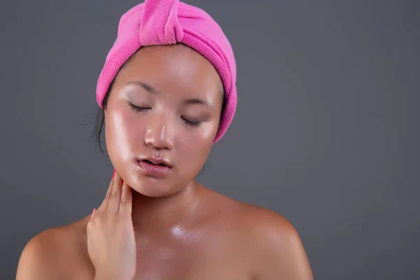 young woman of Chinese ethnicity taking care of her face with face cream
