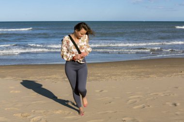 Güzel bir kadın plajda çıplak ayakla yürüyor omzunda minderle
