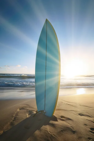surfboard stuck in the beach sand.
