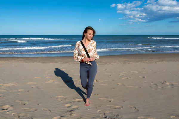 stock image young Caucasian woman walking alone on the sandy beach at sunset