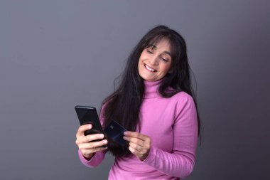 Boğazlı kazaklı kadın, kartlı ve cep telefonlu satın alıyor.