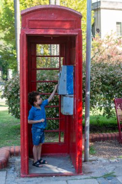Çocuk eski telefon kulübesinde.