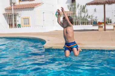 Güneşli bir günde havuza atlayan çocuk