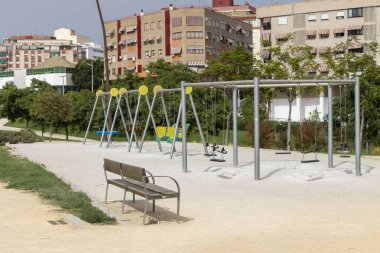 Şehir arkaplanı olan huzurlu bir parkta boş salıncak..