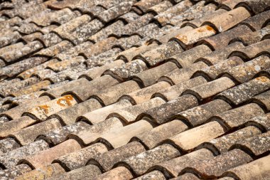 Akdeniz tarzı bir binadaki eski, yıpranmış terracotta çatı fayanslarının detaylı görüntüsü, dokuyu ve eskimiş patinajı gösteriyor..