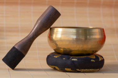 Süslü bir yastığın üzerine yerleştirilmiş Tibet şarkı kasesinin yakın çekimi. Tahta bir çekiçle meditasyonu ve farkındalığı sembolize ediyor..