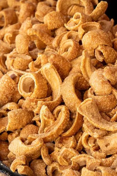 Chicharrones olarak bilinen geleneksel İspanyol domuz derilerinin yakın çekimi, altın, çıtır çıtır dokularını ve kıvrık şekillerini gözler önüne seriyor..
