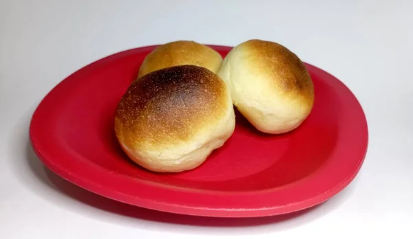 stock image Small round buns on a small red plate with a white background, Photo of the breads with close-up shots