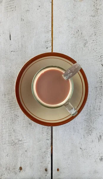 热巧克力牛奶放在杯子里 小白盘放在白木桌上 热巧克力牛奶照片 从上方拍摄 — 图库照片