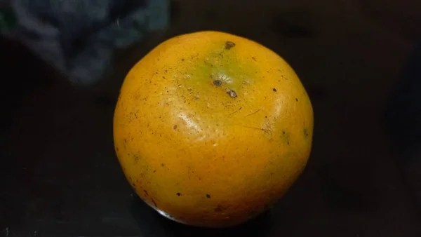 Pomarańcza Kilkoma Plamami Środku Czarnego Stołu — Zdjęcie stockowe