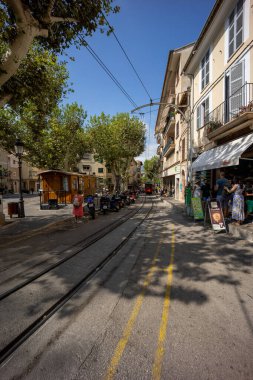 Arka planda tramvay ve elektrik hatları olan geniş açılı bir sokak görüntüsü.