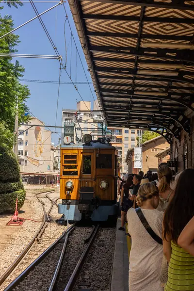 Platformda bekleyen insanlarla birlikte eski istasyona giren eski bir elektrikli tren.