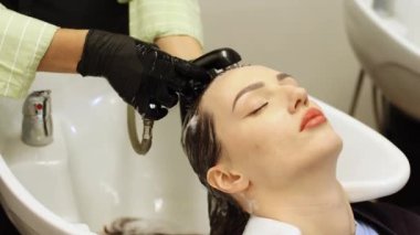 Güzellik salonu çalışanı kuaför saçını şampuan ve suyla yıkıyor. Yüksek kalite 4k görüntü
