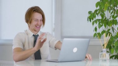 Ofisteki kızıl saçlı genç erkek. Laptopa gülüyor. Neşeli mutlu işçi. Yüksek kalite 4k görüntü
