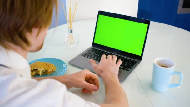 オフィスの赤髪の若い男性労働者 緑色の画面のラップトップ 昼食時に労働者 高品質4K映像 — ストック動画