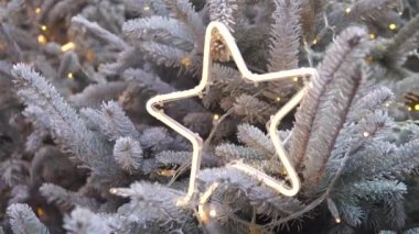 Yılbaşı ağacının yıldız şeklindeki ışığını karlı bir ağacın üzerinde yakmak. Yüksek kalite 4k görüntü