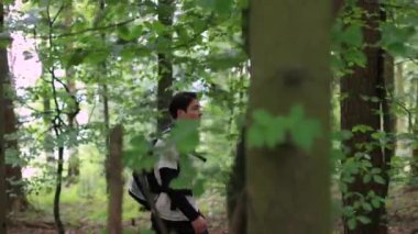 Asyalı bir adam ormanda sırt çantasıyla yürüyor, yandan vurulmuş, ormanda yürüyüşe çıkmış. Yüksek kalite 4k görüntü