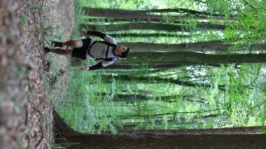 Dikey çekim adamı ormanda dağa tırmanıyor. Adam yaz ormanlarında yürüyor. Yüksek kalite 4k görüntü